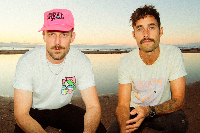 Canadian folk group The East Pointers posing on a beach at sunset.
